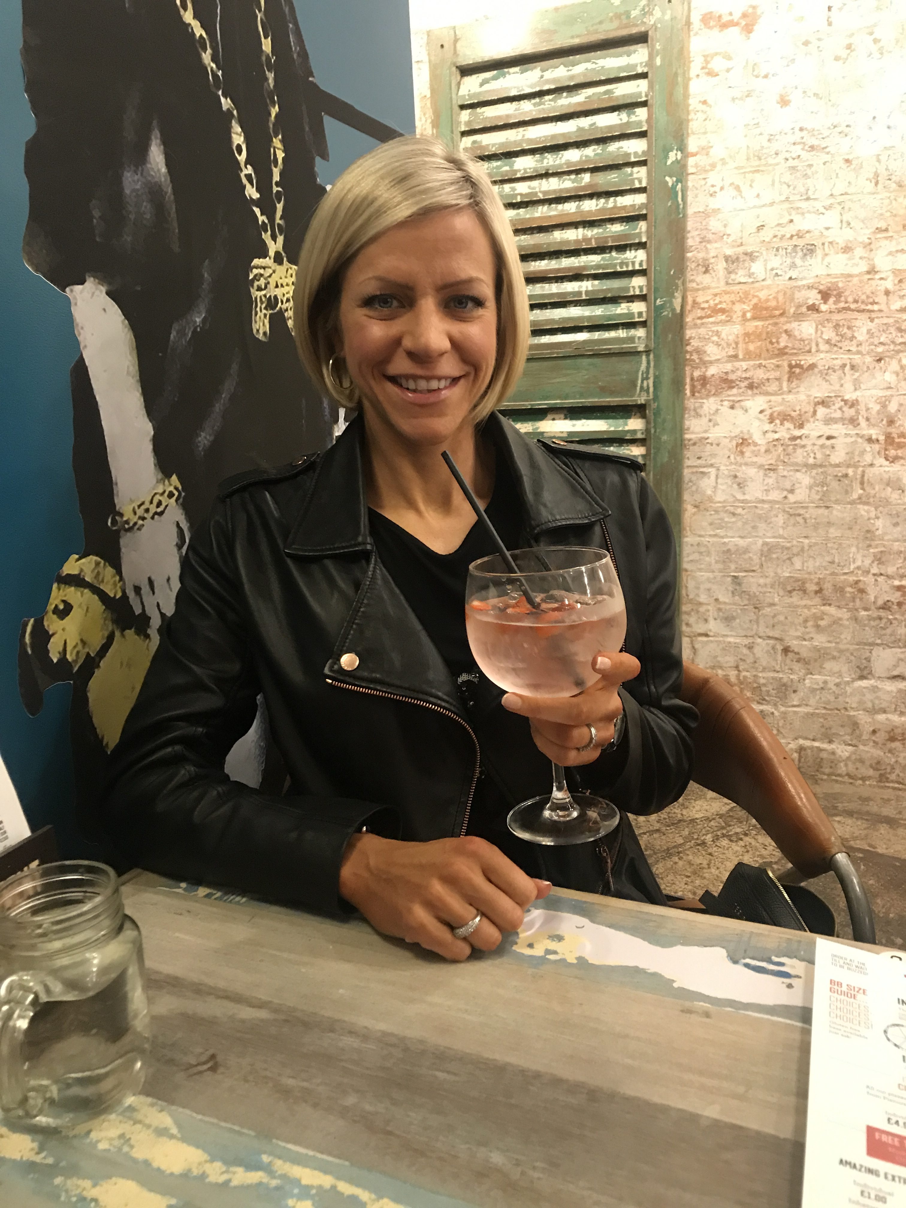 Attractive woman wearing a leather biker jacket relaxes with a drink
